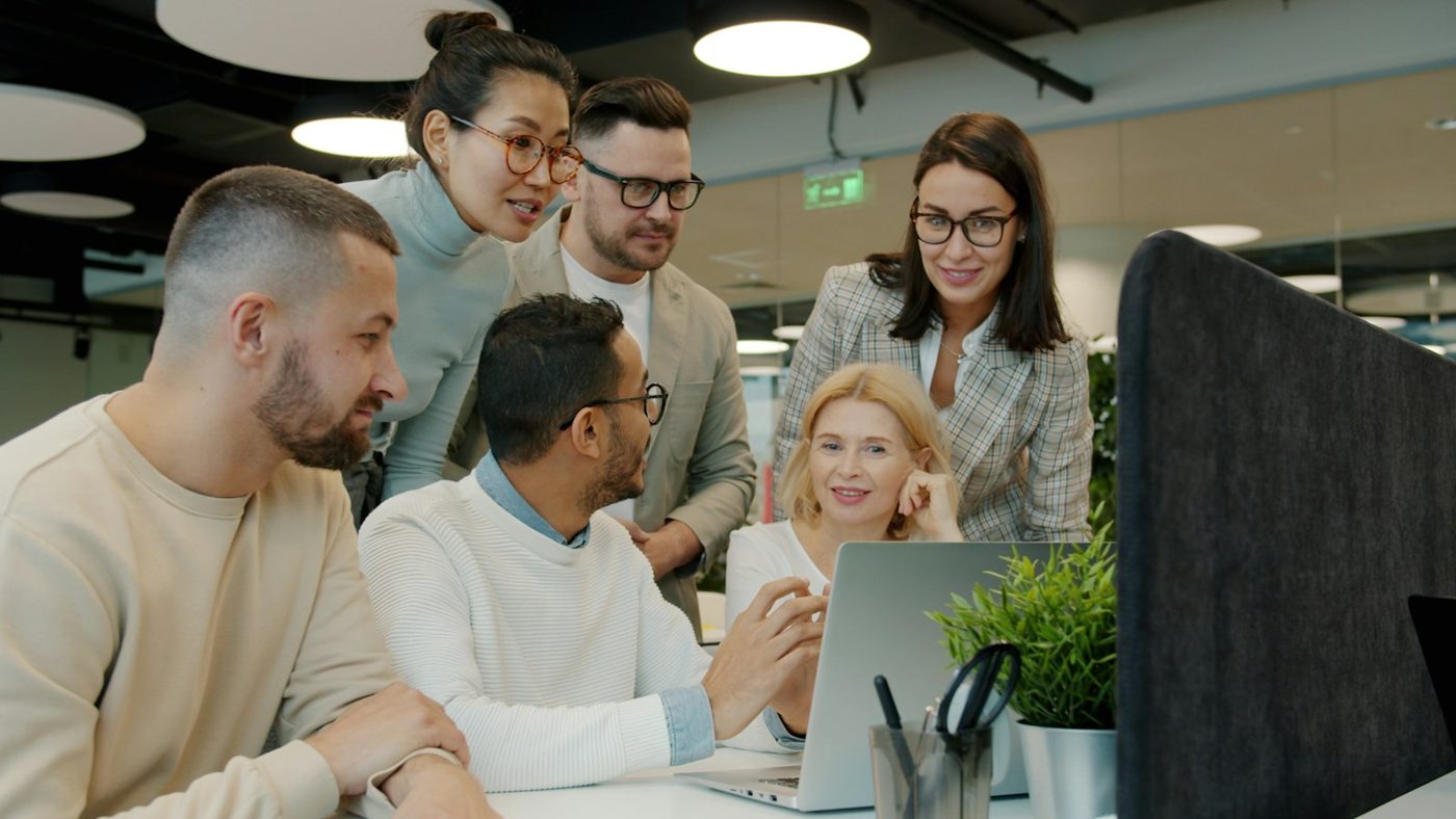 A cross-functional team gathered around a laptop, discussing their work